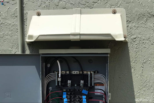 DOORBRIM rain hood mounted above an electric breaker box with door open.
