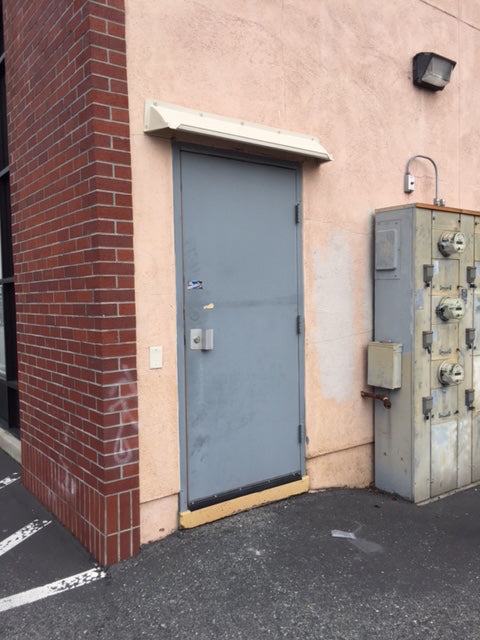 Off white rain diverter mounted above gray hollow metal back door.