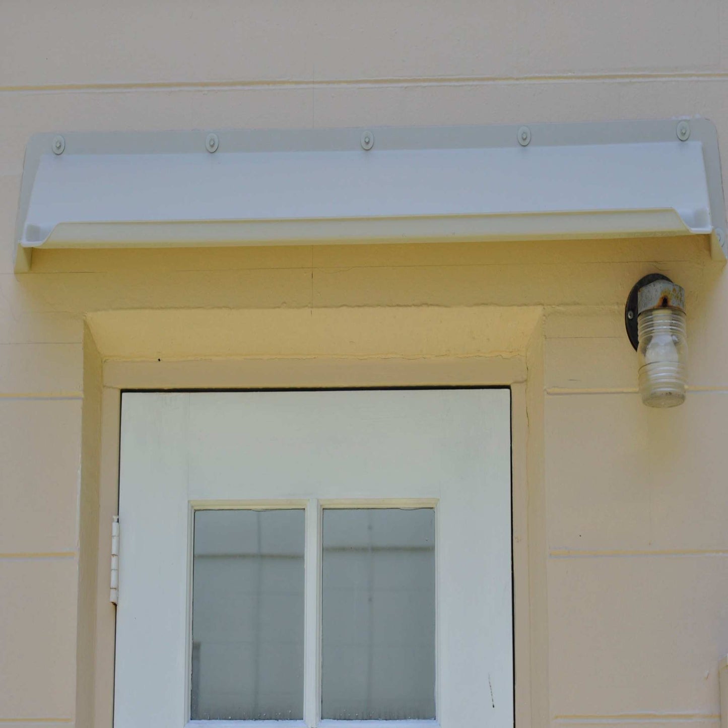 Off white rain diverter mounted above garage side door with 4 light panels.