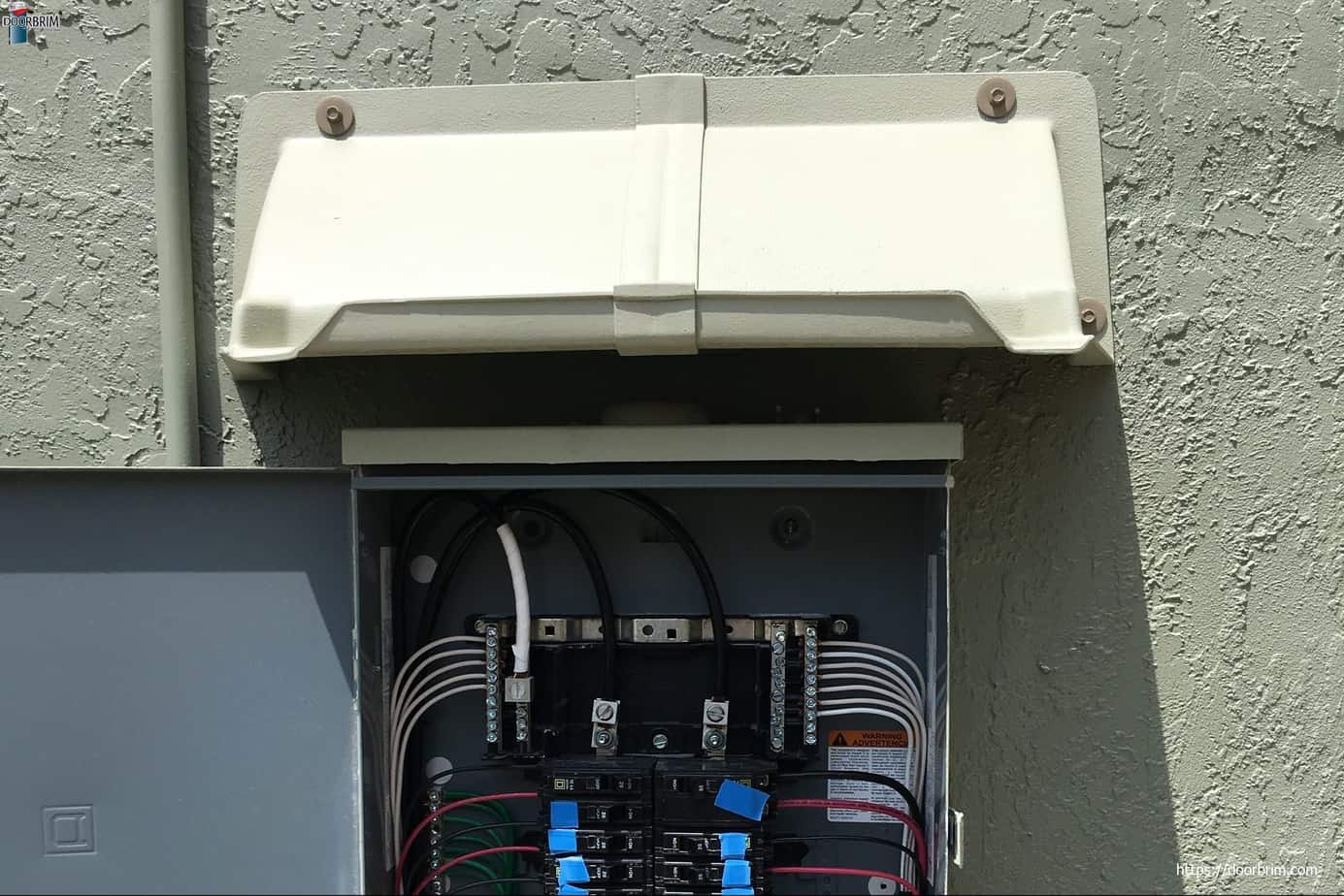 DOORBRIM electric service rain diverter or hood installed over electric meter box.