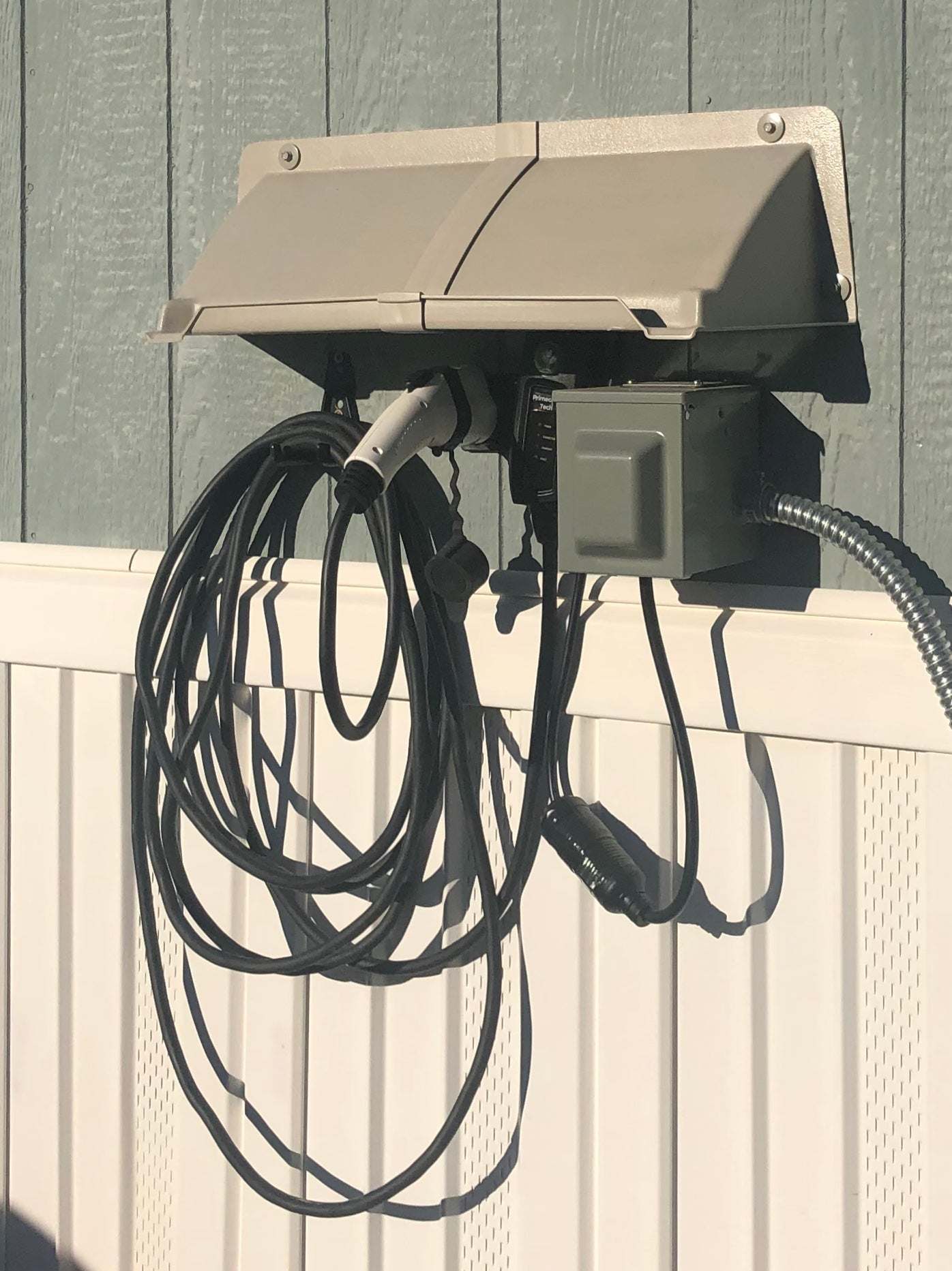 DOORBRIM electric service rain diverter or hood installed over electric EV charger..