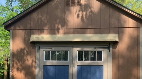 A DOORBRIM SHED RAIN DIVERTER mounted above shed double doors.