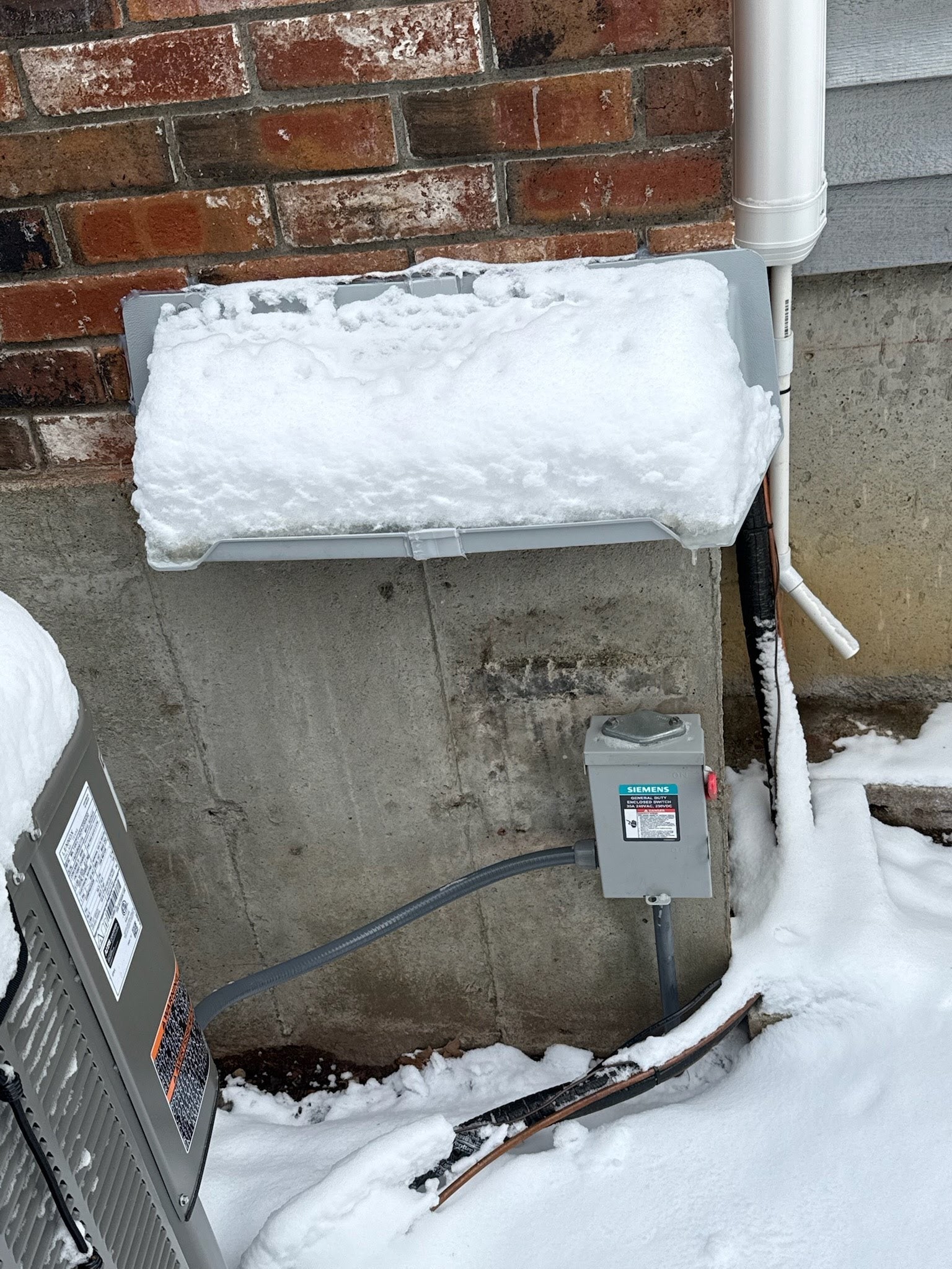 Electric meter rain hood protecting outdoor electric panel from rain and moisture.