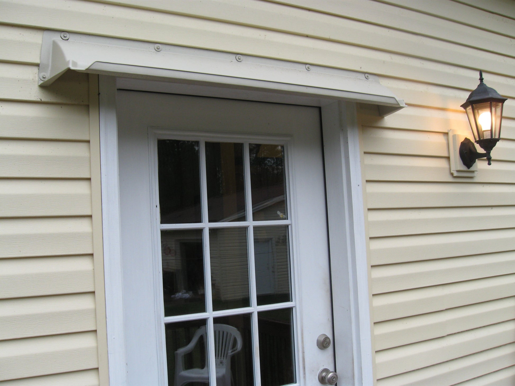 Overhead door rain guard in almond color protecting house entrance with gutter preventing leaks and drips