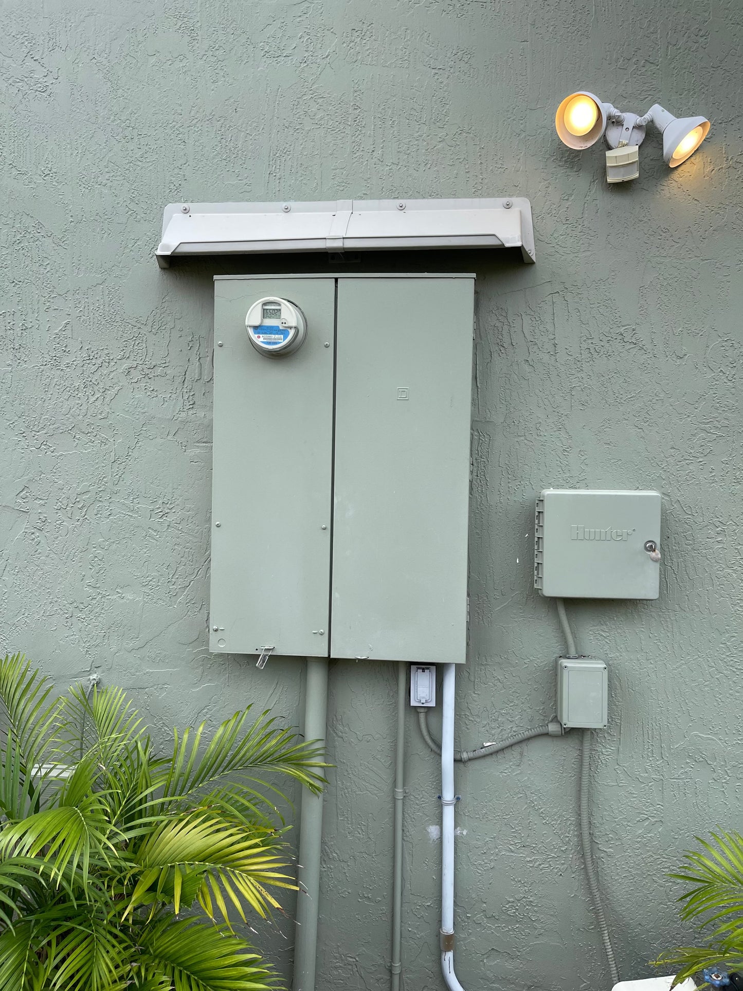 Electric service rain diverter installed on panel with front gutter to prevent water and rust