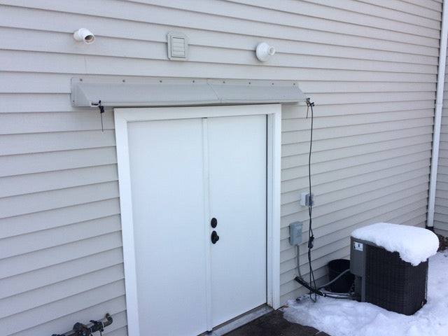 DOORBRIM rain guard and splice bracket above two exterior doors protecting a tele-entry box.