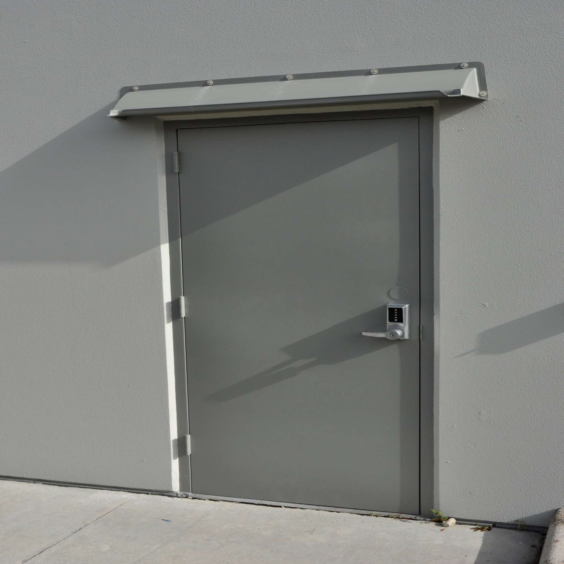 Gray rain diverter mounted above gray single door.
